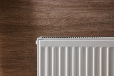 Photo of Modern radiator on wooden wall. Central heating system