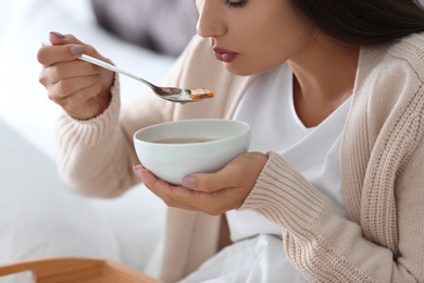 Photo of Sick young woman eating soup to cure flu at home