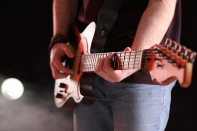 Photo of Man playing electric guitar on stage, closeup. Rock concert