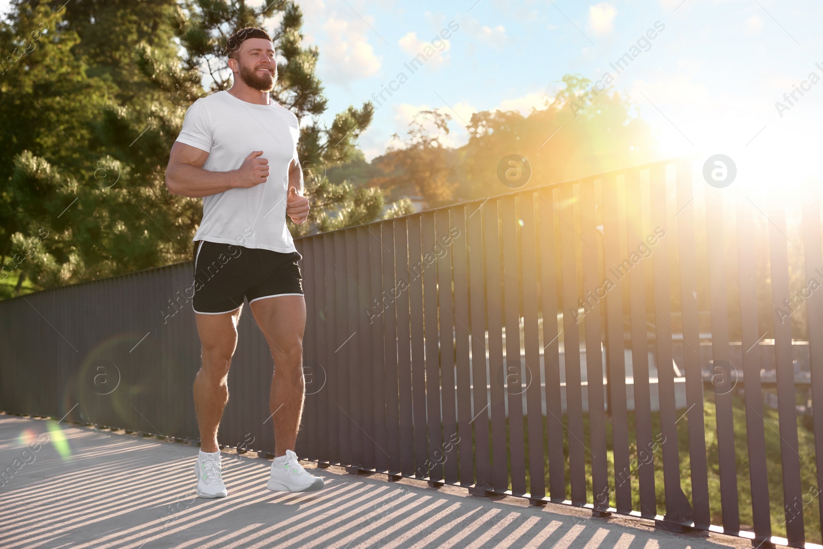 Photo of Young man running outdoors on sunny day. Space for text