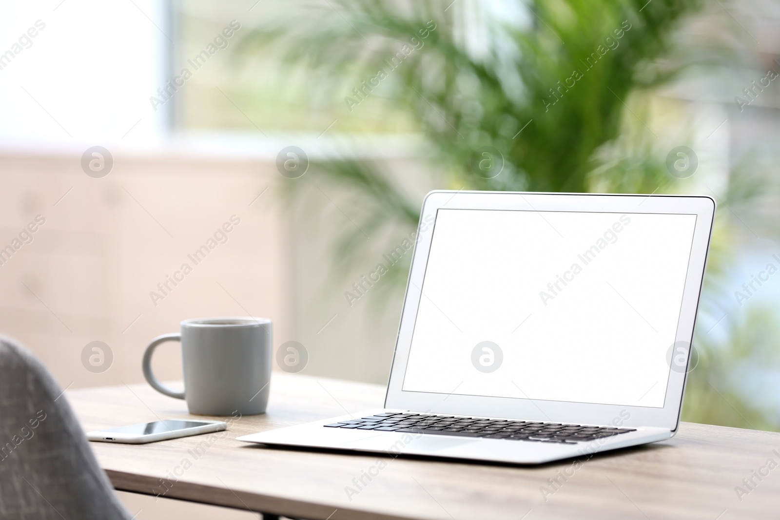 Photo of Modern laptop on desk in room. Home workplace