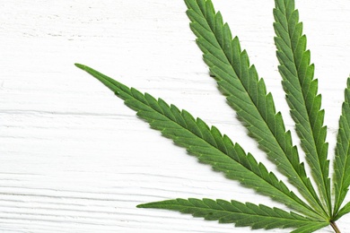 Photo of Leaf of medical hemp on white wooden background, top view