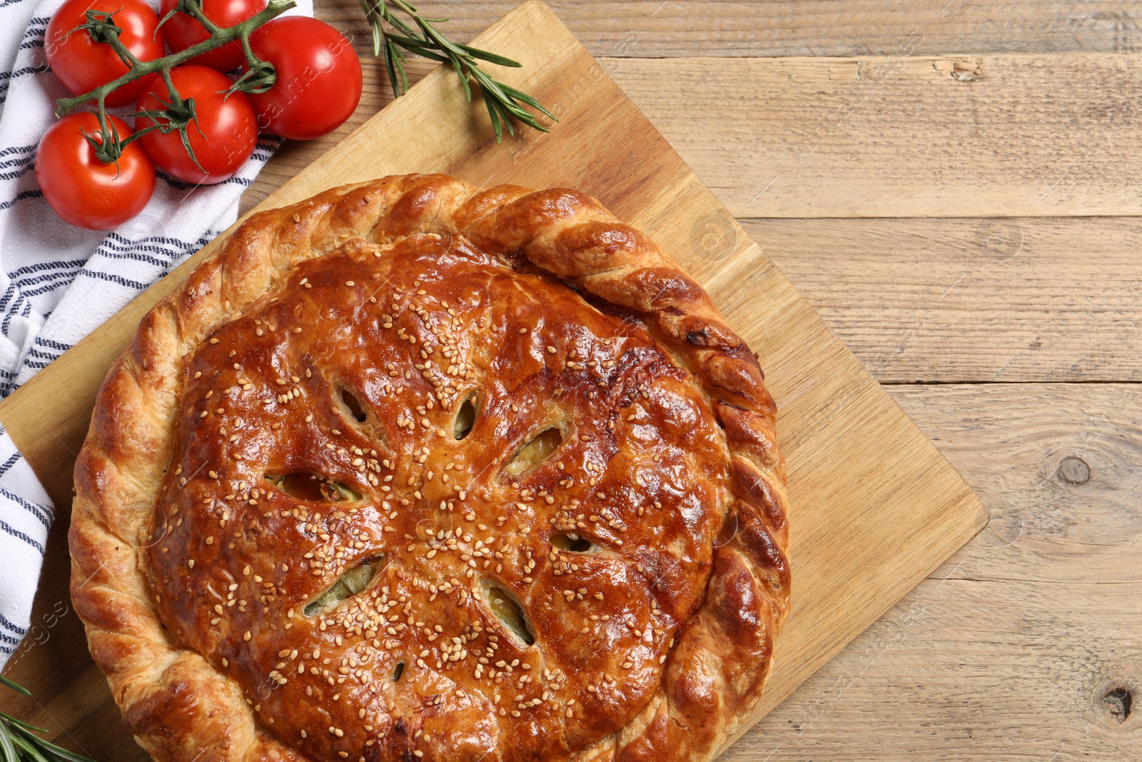 Photo of Tasty homemade pie, rosemary and tomatoes on wooden table, flat lay. Space for text