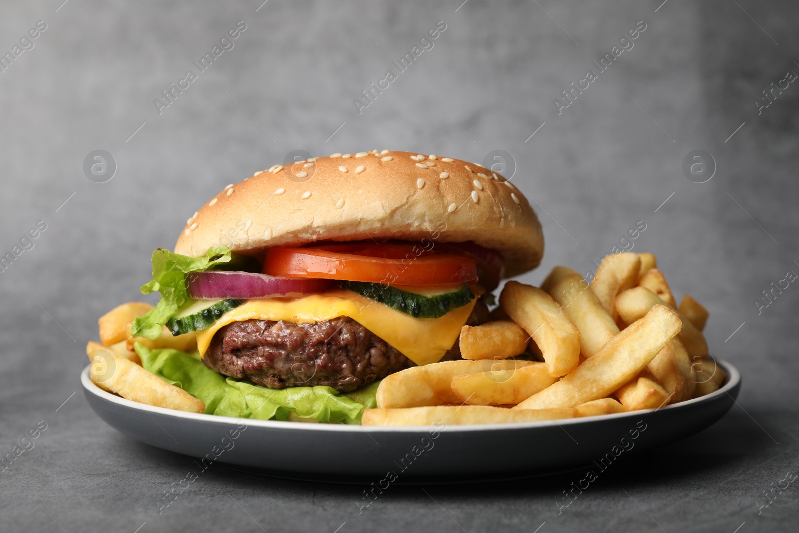 Photo of Delicious burger and french fries on grey textured background