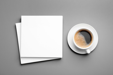 Photo of Blank paper sheets for brochure and cup of coffee on grey background, flat lay. Mock up