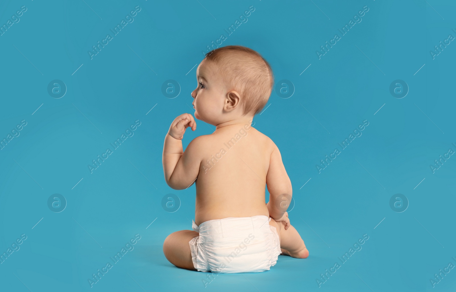 Photo of Cute little baby in diaper on light blue background. Space for text