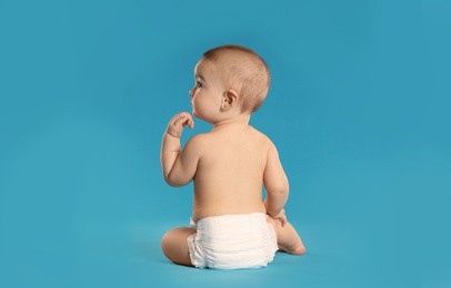 Cute little baby in diaper on light blue background. Space for text