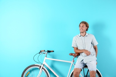 Photo of Handsome man with bicycle against color background. Space for text