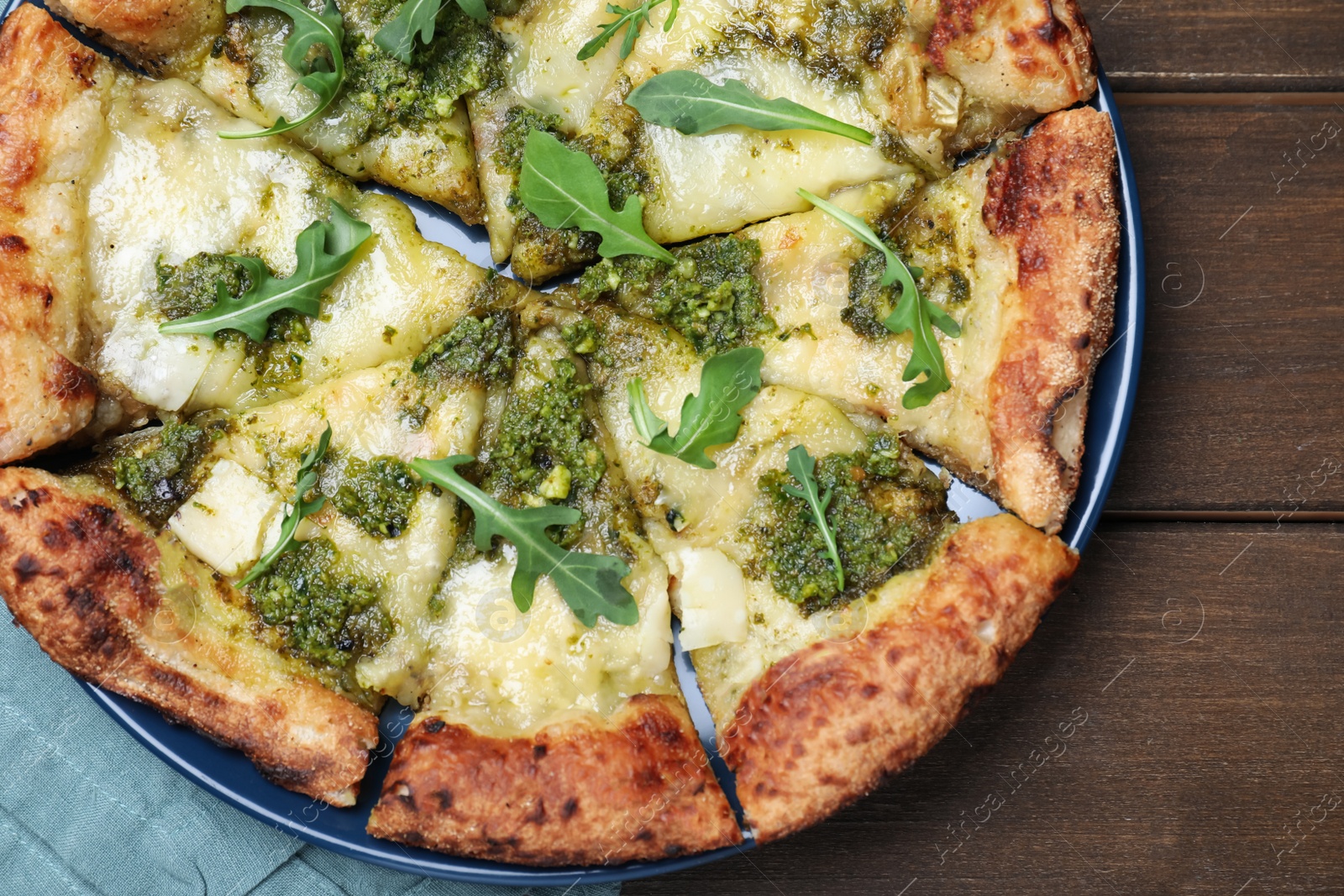 Photo of Delicious pizza with pesto, cheese and arugula on wooden table, top view