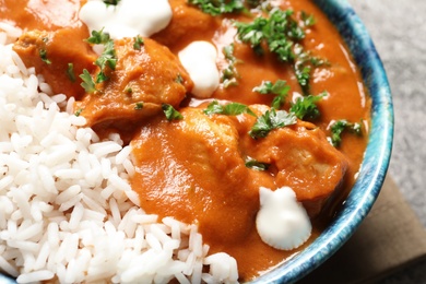Photo of Bowl of butter chicken with rice on table, closeup