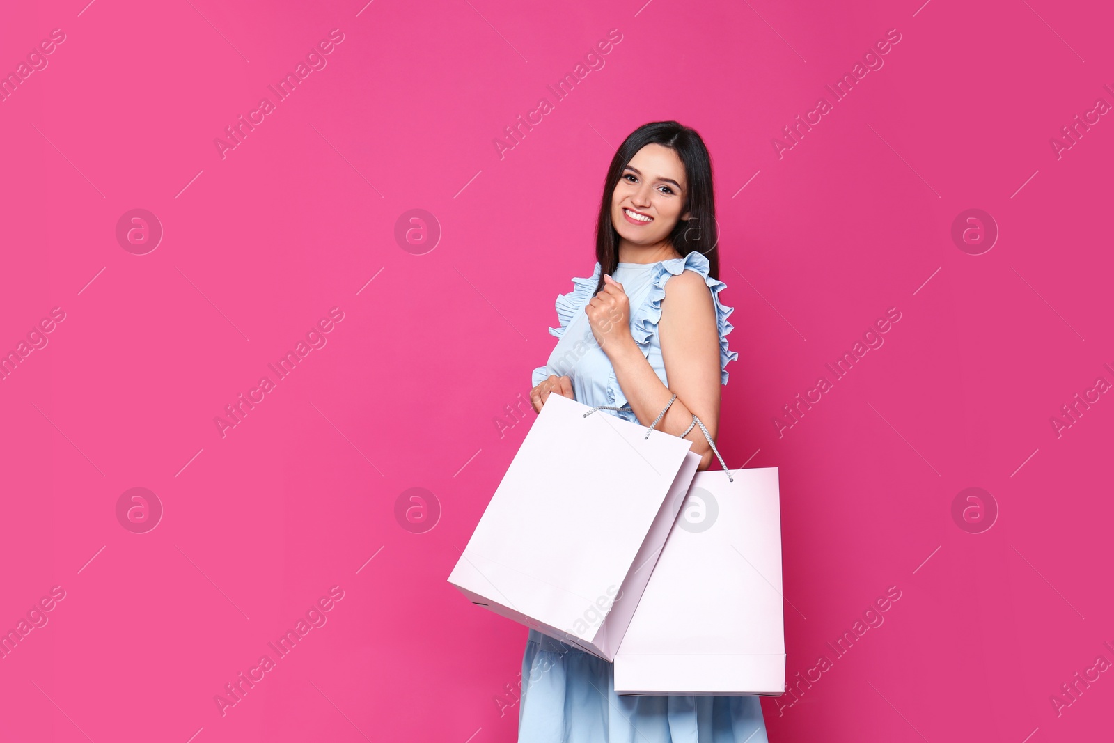 Photo of Beautiful young woman with blank paper bags against color background, space for text