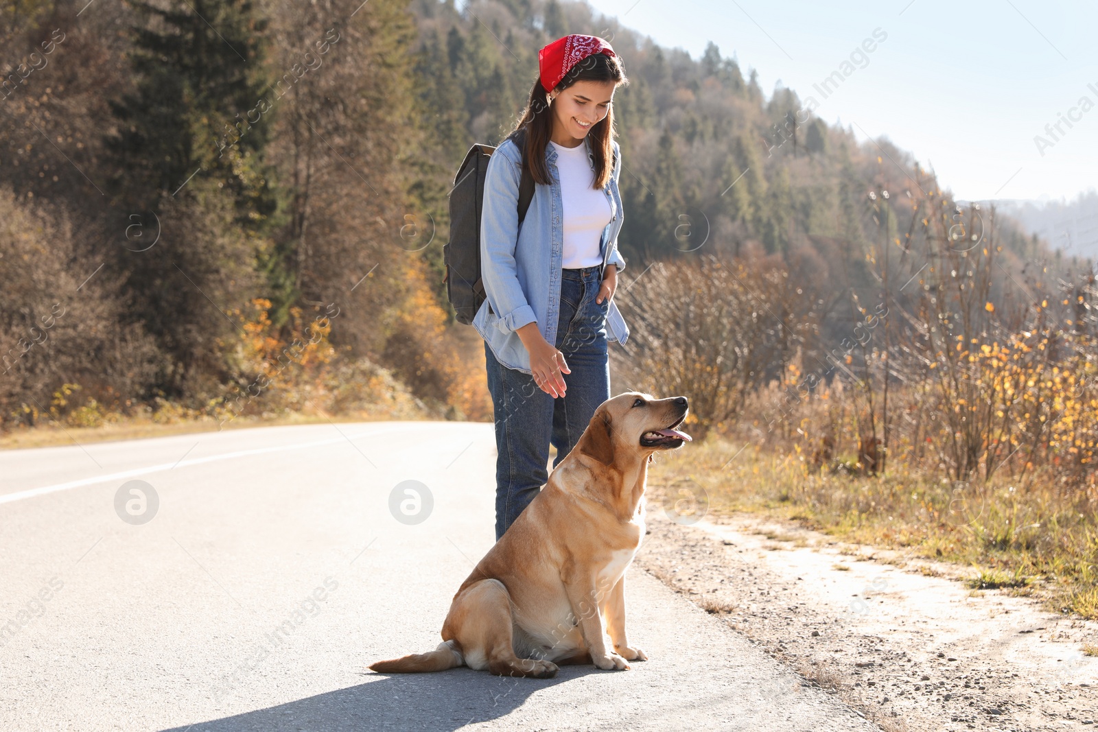 Photo of Happy woman and adorable dog on road. Traveling with pet