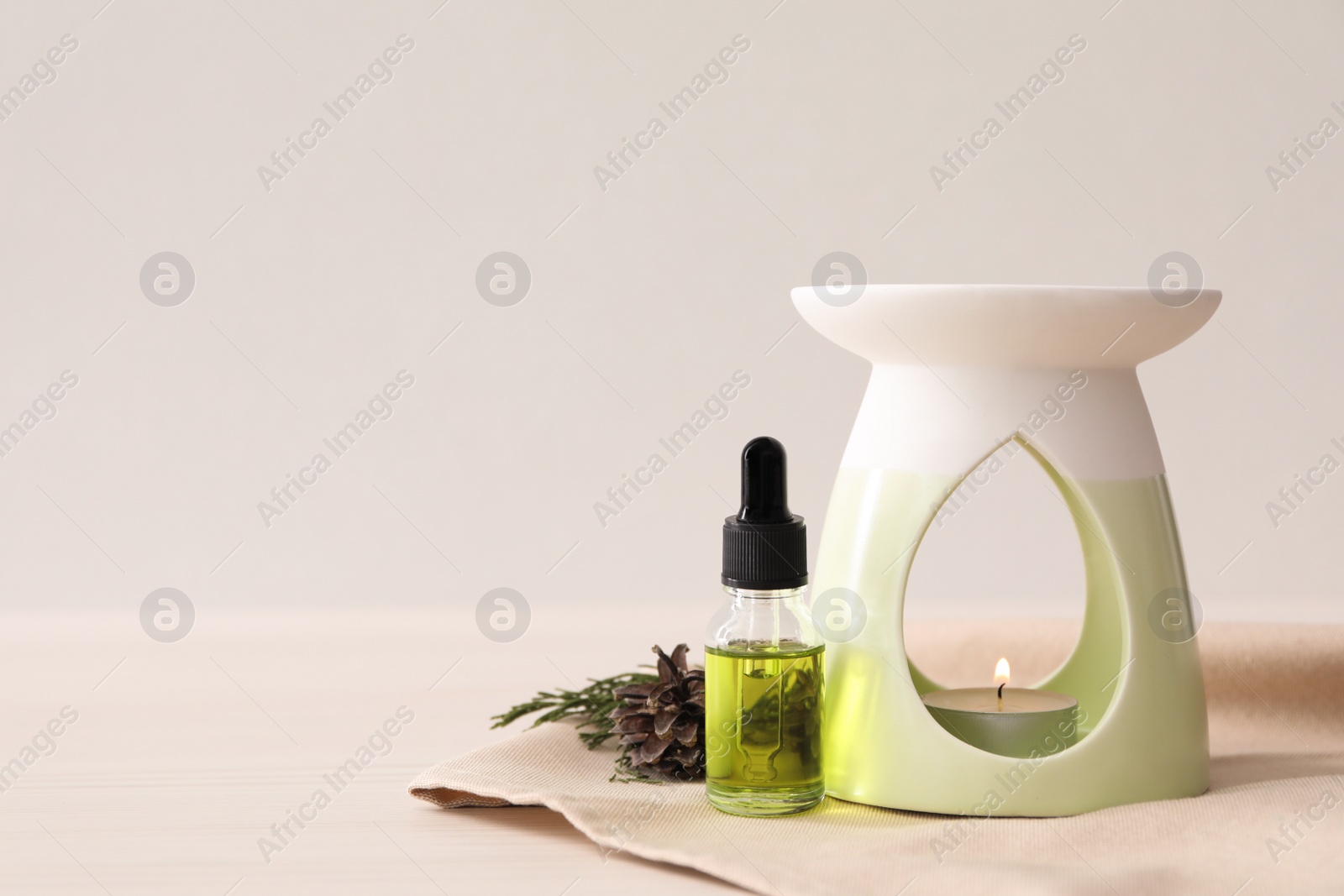 Photo of Aroma lamp with coniferous essential oil on white wooden table, space for text