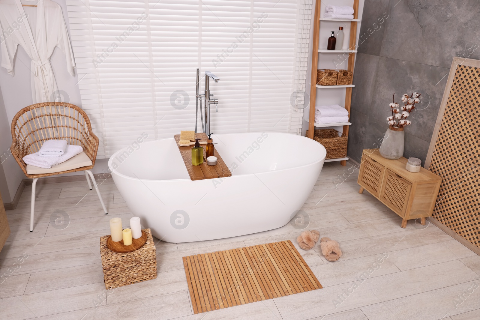 Photo of Stylish bathroom interior with bamboo bath mat and white tub