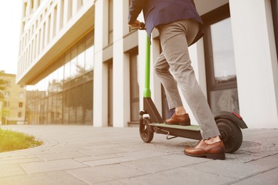 Photo of Businessman riding modern kick scooter on city street, closeup. Space for text