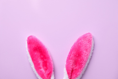 Easter bunny ears on violet background, top view. Space for text