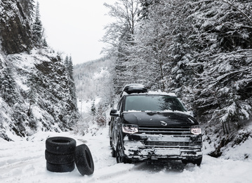 Snow tires near car on road in winter