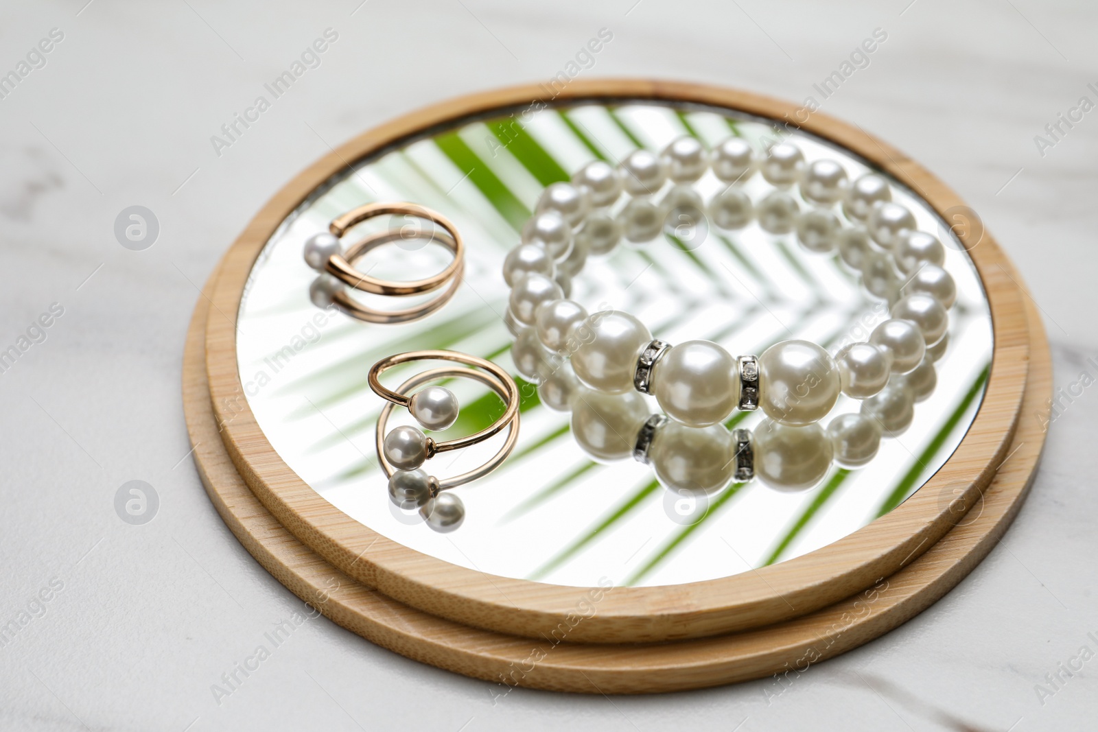 Photo of Elegant bracelet and earrings with pearls on white marble table