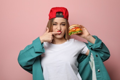 Photo of Pretty woman with tasty burger on color background