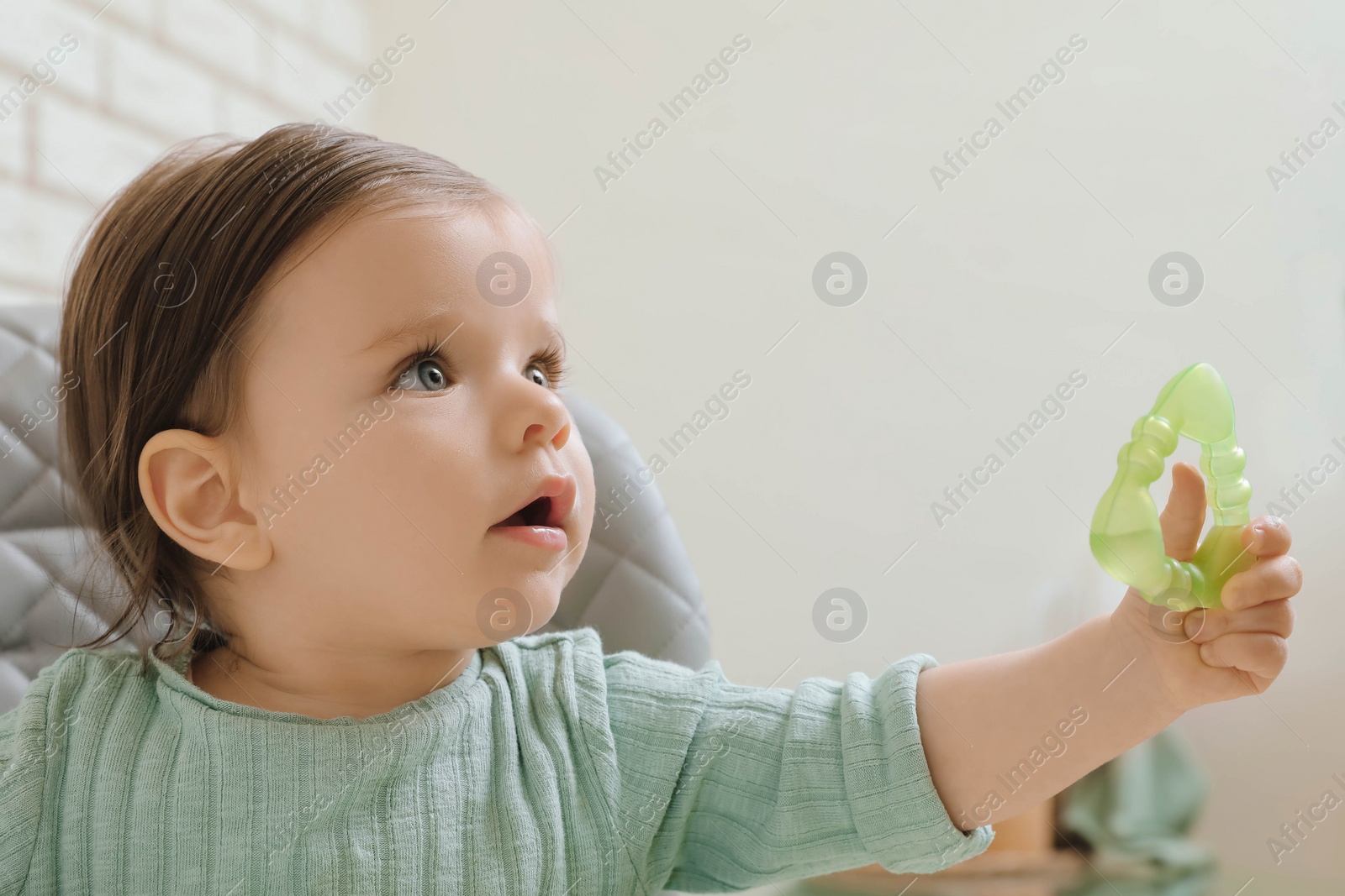 Photo of Cute little baby with teether in high chair indoors