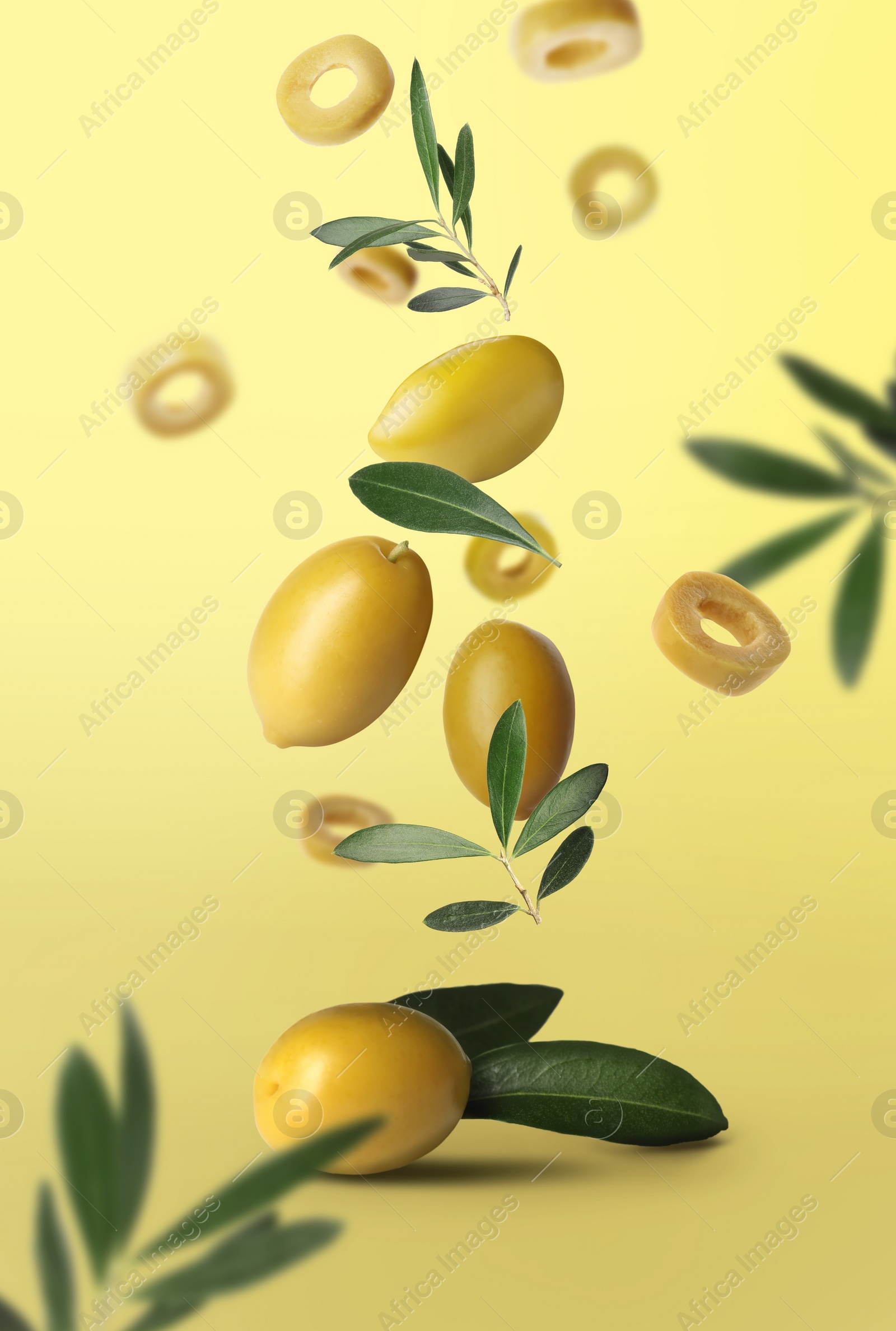 Image of Fresh olives and leaves falling on pale yellow background