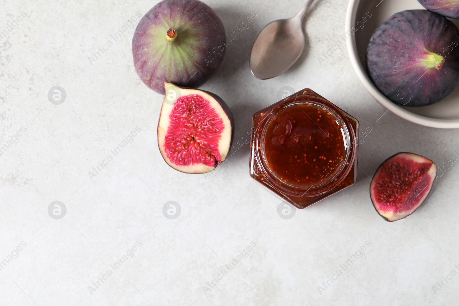 Photo of Jar of tasty sweet jam, fresh figs and spoon on white table, flat lay. Space for text