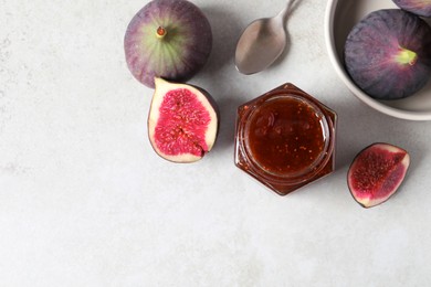 Jar of tasty sweet jam, fresh figs and spoon on white table, flat lay. Space for text