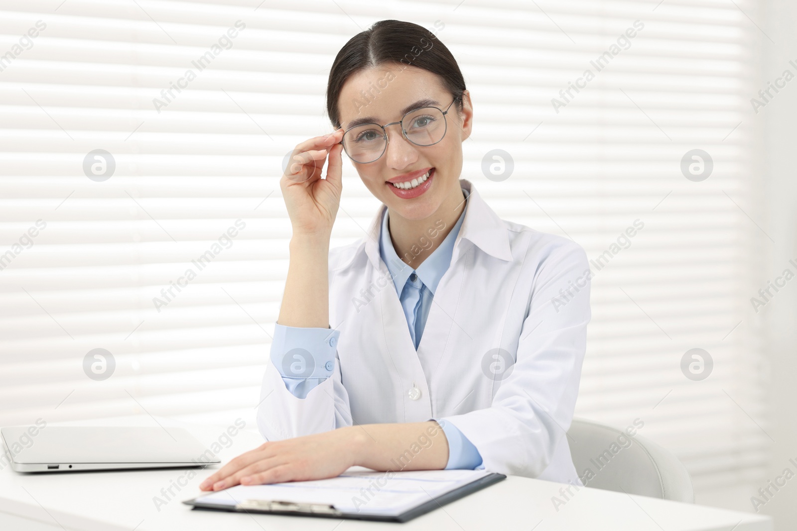 Photo of Medical consultant with glasses at table in clinic