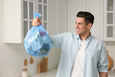 Photo of Man holding full garbage bag at home