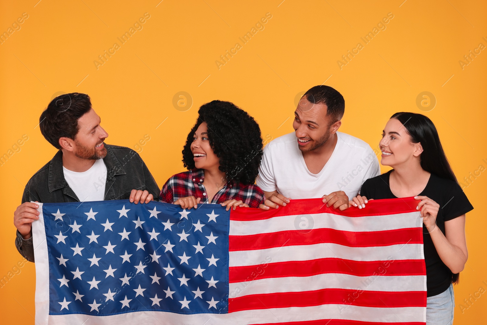 Photo of 4th of July - Independence Day of USA. Happy friends with American flag on yellow background