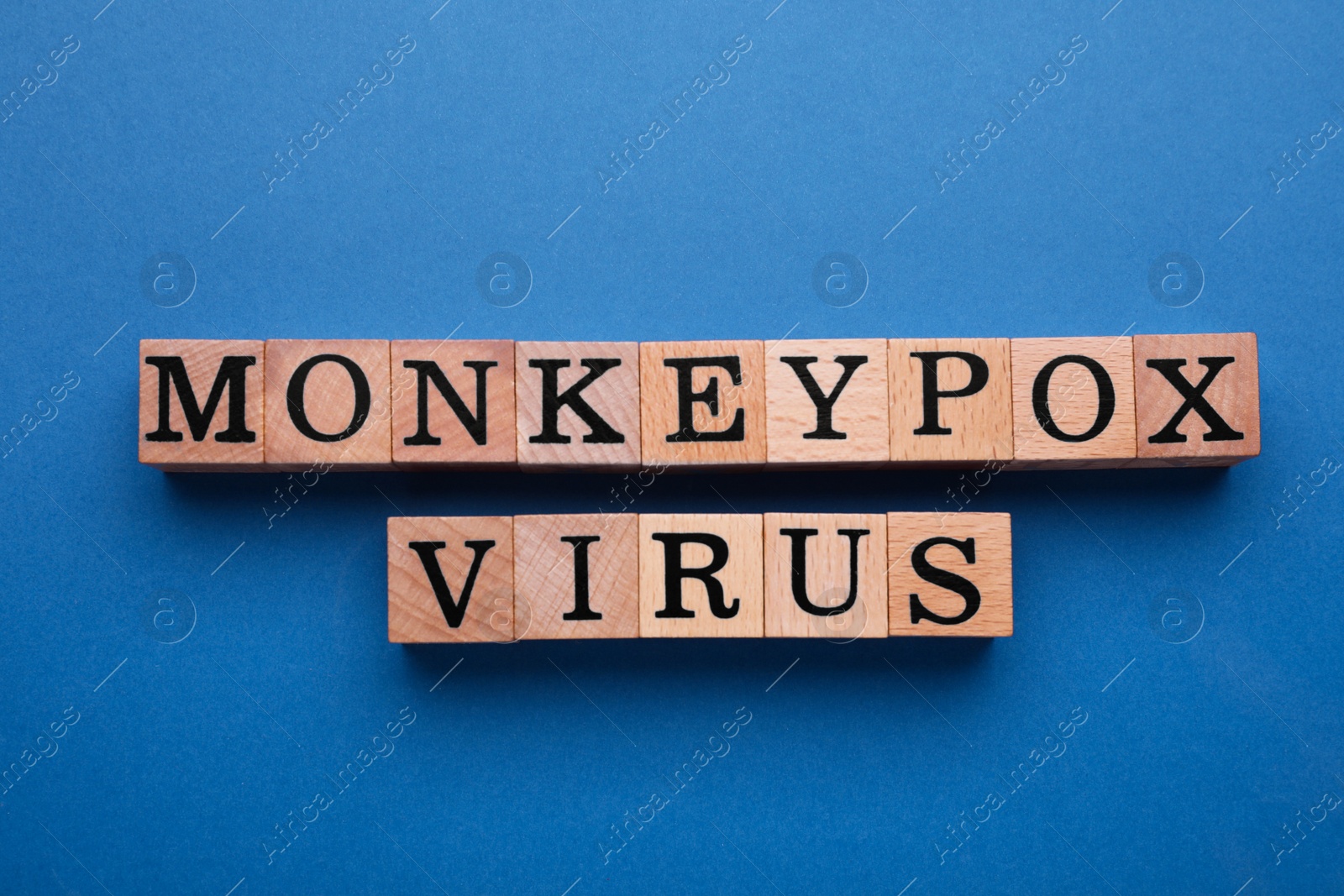 Photo of Words Monkeypox Virus made of wooden cubes on blue background, flat lay