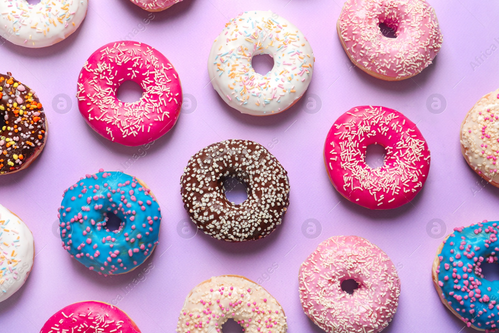 Photo of Delicious doughnuts with sprinkles on color background, top view