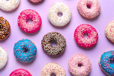 Photo of Delicious doughnuts with sprinkles on color background, top view