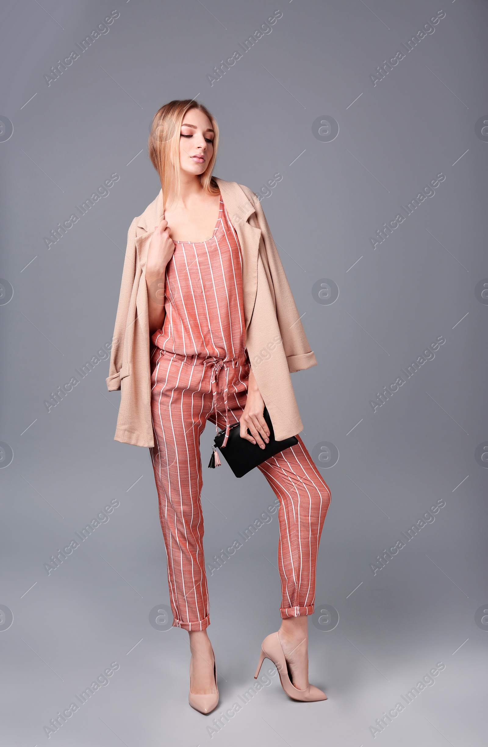 Photo of Young stylish woman in trendy shoes with bag on grey background