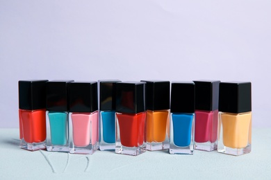 Photo of Bright nail polishes on table against color background. Space for text