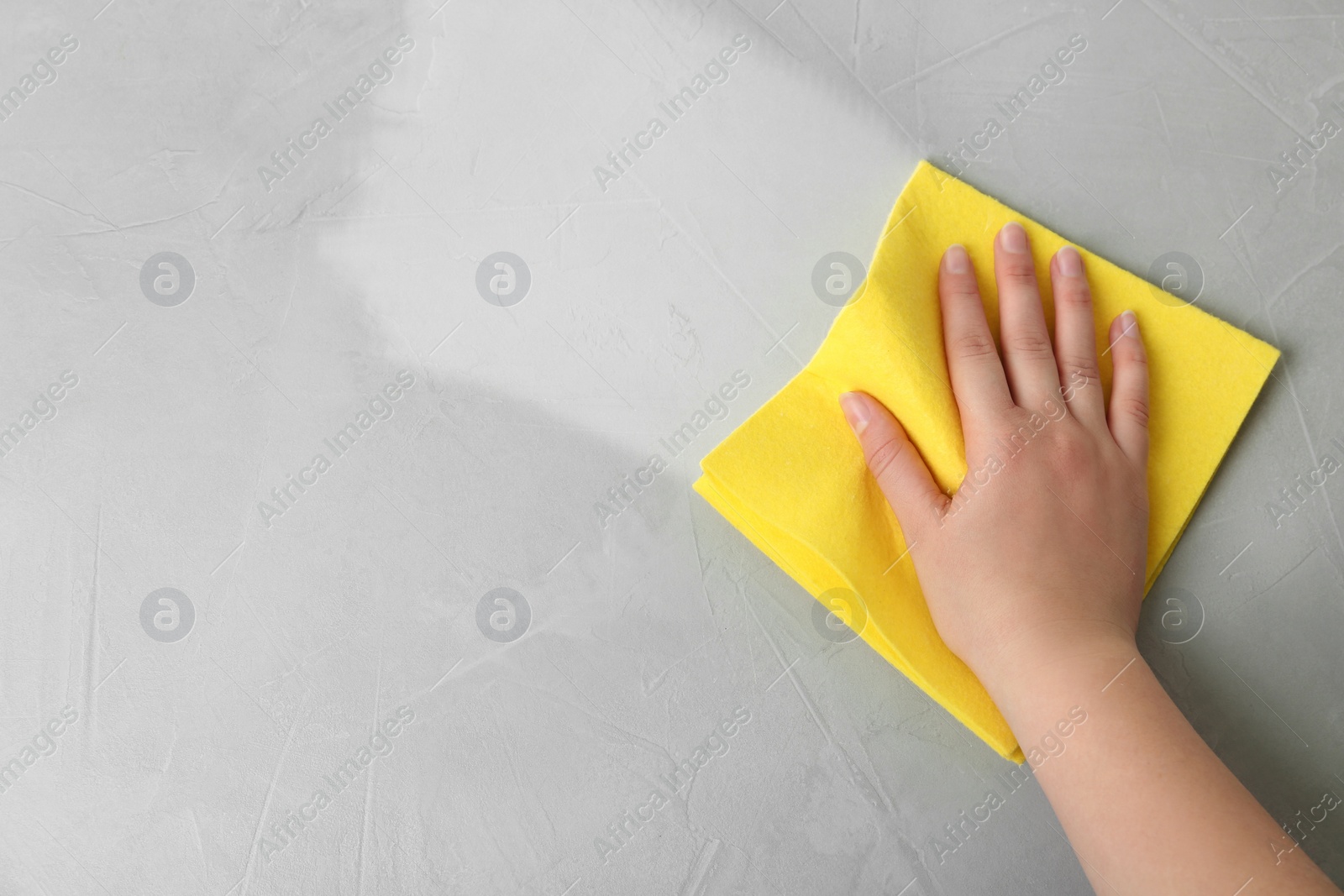 Image of Woman wiping grey table with rag, top view. Cleaning service 