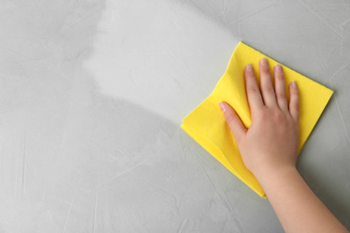 Image of Woman wiping grey table with rag, top view. Cleaning service 