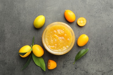 Delicious kumquat jam and fresh fruits on grey table, flat lay