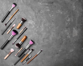 Photo of Flat lay composition with professional brushes for different makeup products on grey background
