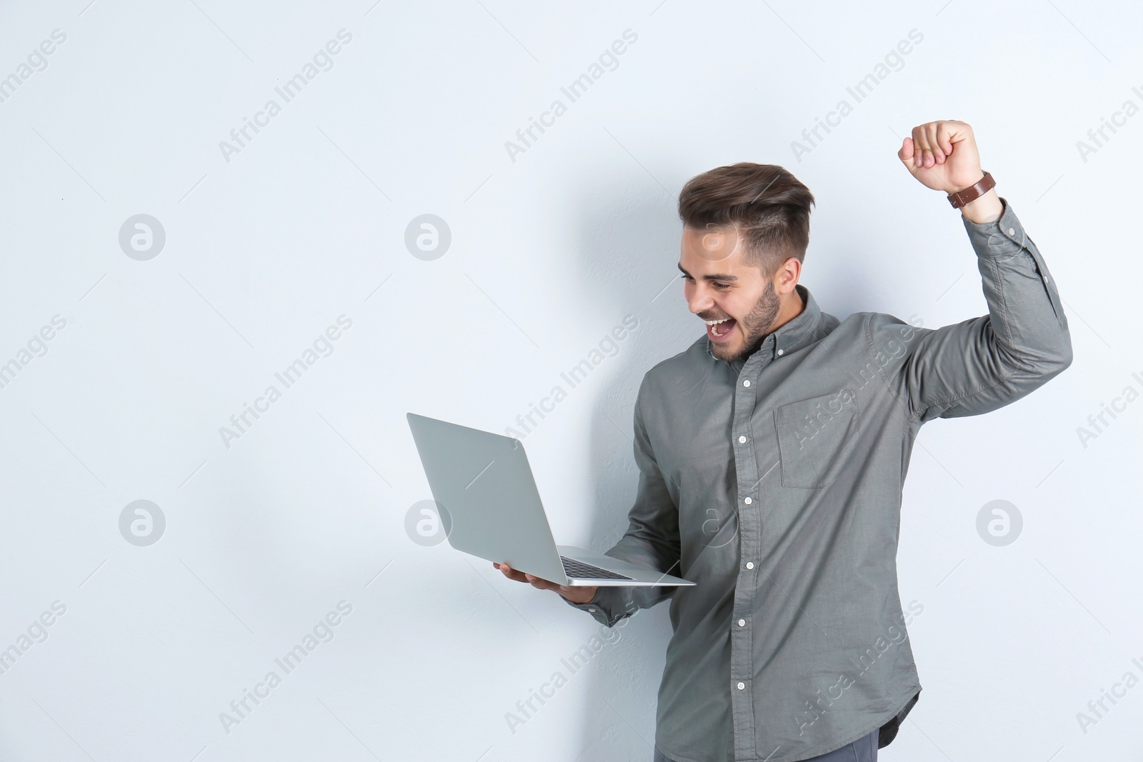 Photo of Emotional man with laptop on light background