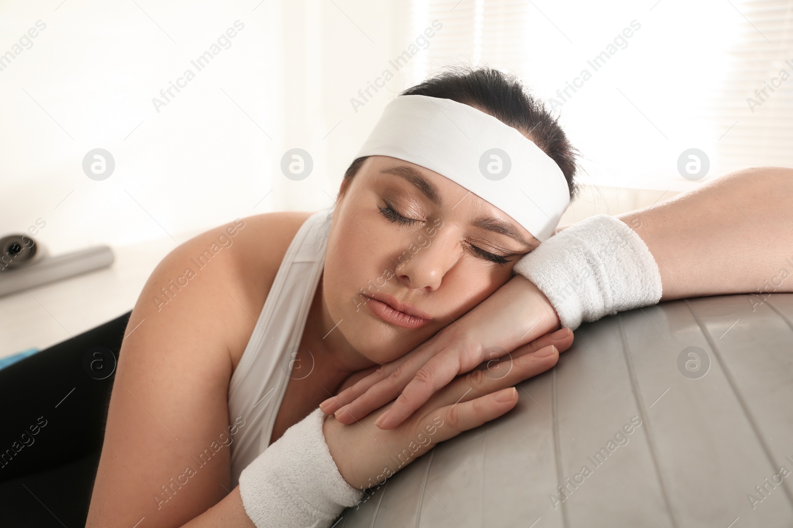 Photo of Lazy overweight woman leaning on fit ball instead of training at gym