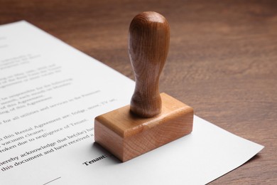 One stamp tool and document on wooden table, closeup