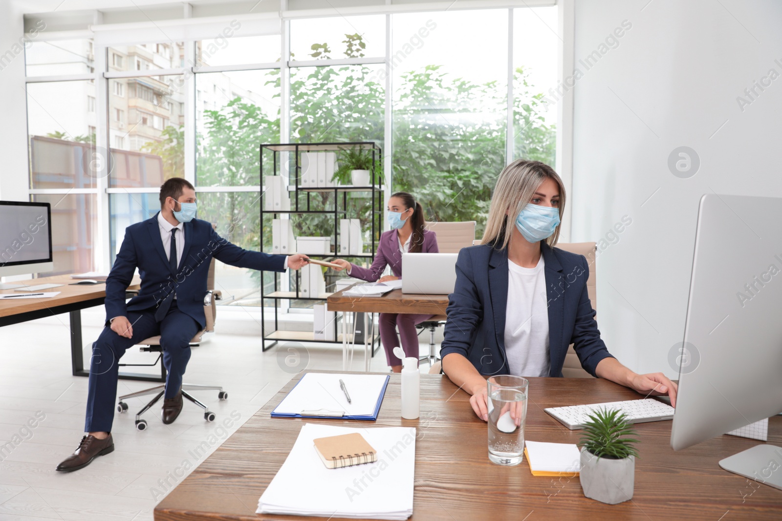 Photo of Office employees in respiratory masks at workplace