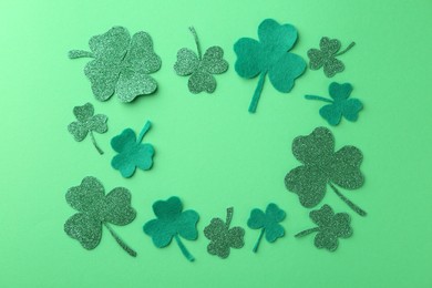 Photo of St. Patrick's day. Frame of decorative clover leaves on green background, flat lay. Space for text