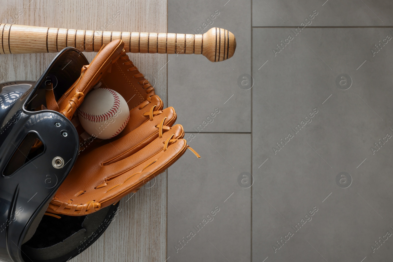 Photo of Baseball bat, batting helmet, leather glove and ball on wooden bench indoors, top view. Space for text