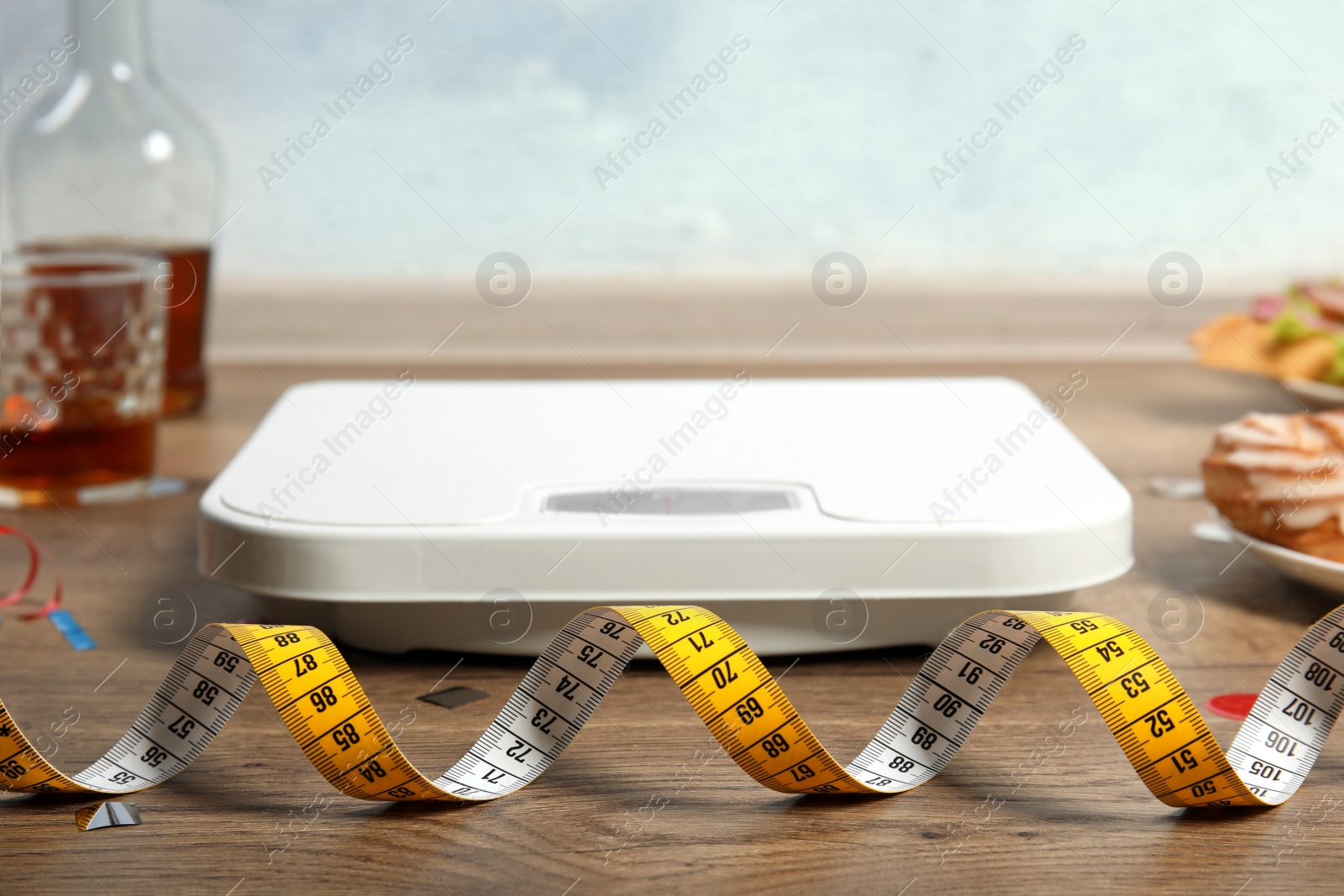 Photo of Scale, tape measure and food after party on floor. Overweight problem