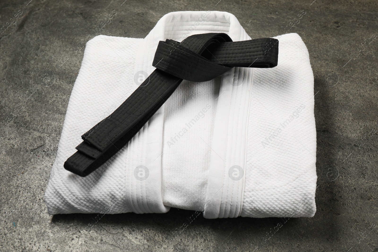 Photo of Black karate belt and white kimono on gray background