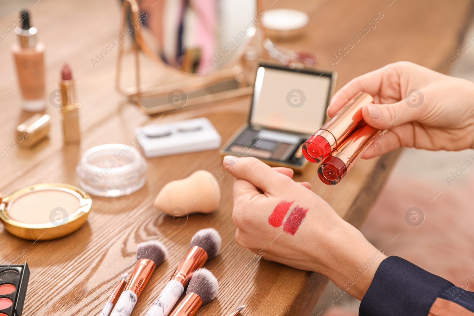 Photo of Beauty blogger with lipstick swatches at table, closeup