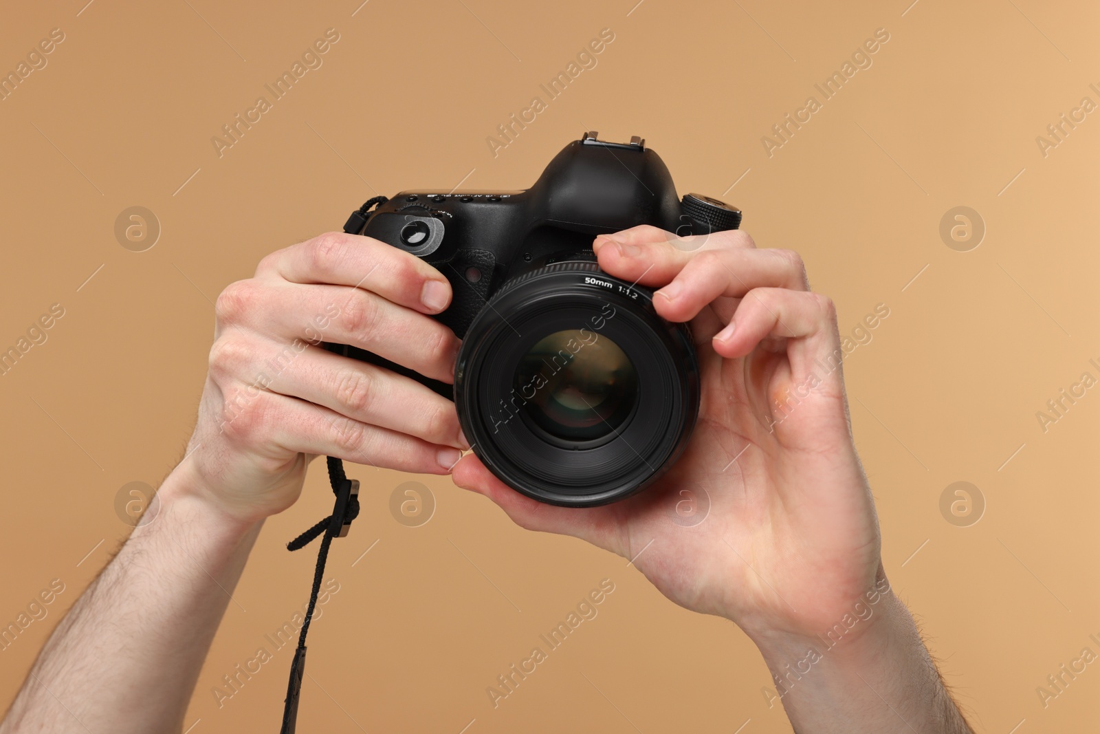 Photo of Photographer holding camera on beige background, closeup