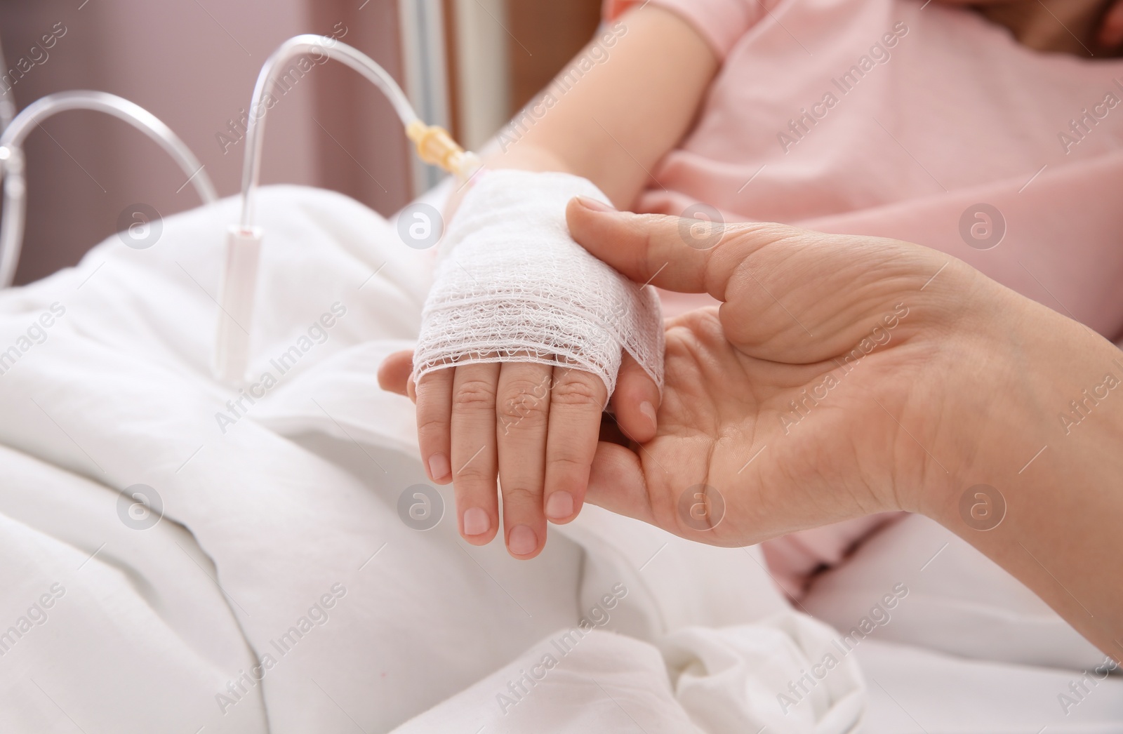 Photo of Doctor holding little child's hand with intravenous drip in hospital, closeup